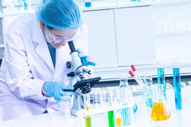 Asya kadın bilim adamı, araştırmacı, teknisyen veya öğrenci tıbbi, Kimya veya biyoloji laboratuarında Bilimsel ekipman olan mikroskop kullanarak araştırma veya deney yaptı