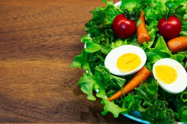 Beyaz tabak ve ahşap tabakta taze sebze salatası. Yeşil sebzeli havuç ve yumurta karışımı balzamik salata sağlıklı bir yemektir.