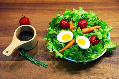 Beyaz tabak ve ahşap tabakta taze sebze salatası. Yeşil sebzeli havuç ve yumurta karışımı balzamik salata sağlıklı bir yemektir.
