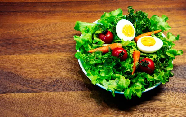 Beyaz tabak ve ahşap tabakta taze sebze salatası. Yeşil sebzeli havuç ve yumurta karışımı balzamik salata sağlıklı bir yemektir.