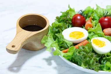 Beyaz tabak ve ahşap tabakta taze sebze salatası. Yeşil sebzeli havuç ve yumurta karışımı balzamik salata sağlıklı bir yemektir.