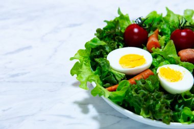 Beyaz tabak ve ahşap tabakta taze sebze salatası. Yeşil sebzeli havuç ve yumurta karışımı balzamik salata sağlıklı bir yemektir.