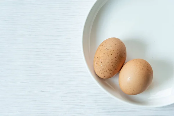 Raw fresh chicken eggs or boiled eggs  or boiled eggs on whith plate isolated white gray line texture background