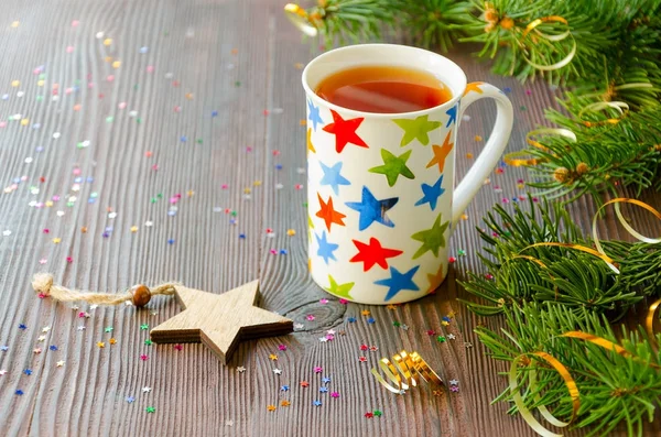 Рождественский черный чай в кружке с разноцветными звездами и рождественским убранством — стоковое фото