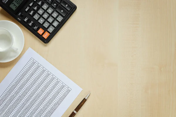 Hesap makinesi, belge, fincan kahve ve bir kalem