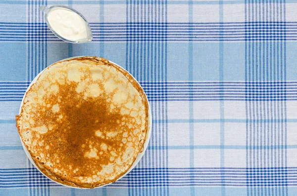 在格子桌布上加酸奶奶油的俄罗斯薄饼 — 图库照片
