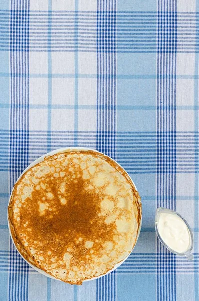 在格子桌布上加酸奶奶油的俄罗斯薄饼 — 图库照片