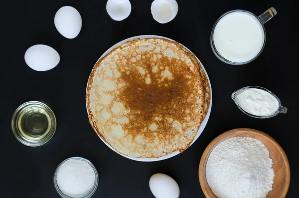 Siyah arka plan üzerine yemek pişirmek için malzemeler ile Rus krep