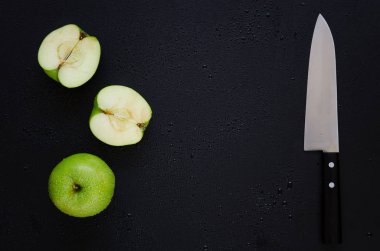 Yeşil elma, elma ve siyah arka plan üzerinde bıçak iki yarısı