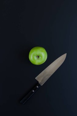 Yeşil elma ve siyah arka plan üzerinde bıçak
