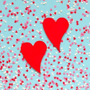 Arka plan mavi renkli kalpler olan iki kırmızı kalp