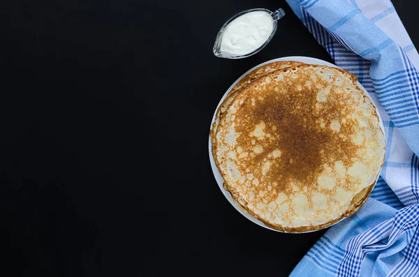 Pancake Rusia dan krim asam dengan serbet checker di latar belakang hitam . — Stok Foto