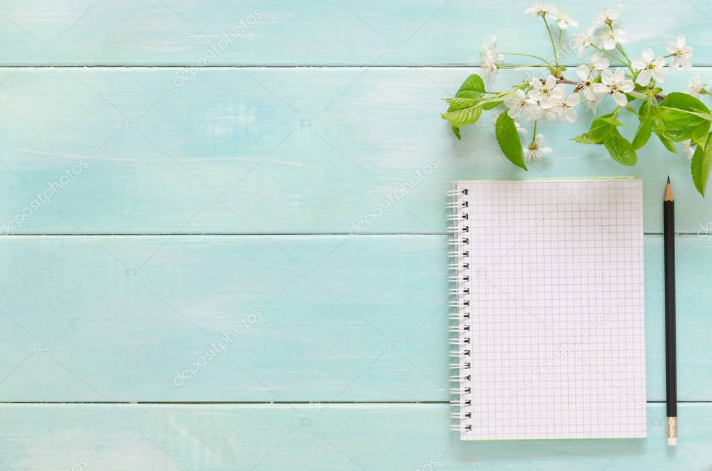 Open notebook with pencil and sprig with cherry blossoms