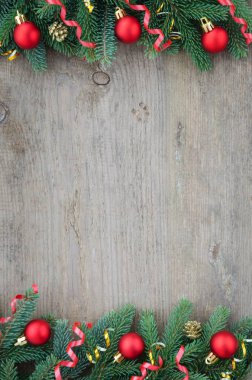 Spruce dalları, kırmızı Noel oyuncakları ve eski ahşap masa şeritleriyle çevrili.