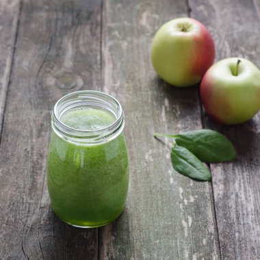 Cam bir kavanozda yeşil smoothie, ahşap bir masada elma ve ıspanak. Sağlıklı bir yaşam tarzı. Seçici odak