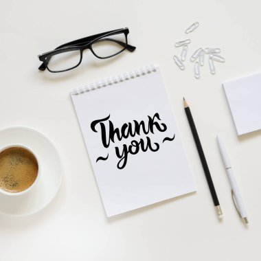 Çalışma alanı kalem, kağıt, kahve fincanı, bardak ve ofis malzemeleri. Üst kattaki daire tepemizde duruyordu. Siyah harfler. Teşekkürler.