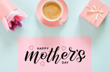 Bir buket dengeli çiçek, bir fincan kahve ve mavi arka planda hediye kutusu. Anneler günün kutlu olsun.