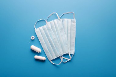 Mavi arka planda dikiş iplikleri olan yüz maskeleri. Kişisel Koruyucu Ekipman.