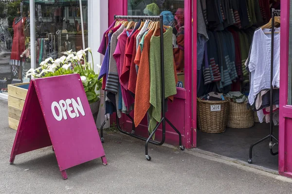 Brightly colored Open sign outside a shop selling clothes, on a sunny day in London, UK