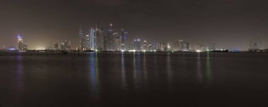 Geceleri Dubai Marina 'nın gökdelenleri. Modern binaların ışıkları, binaların önündeki Basra Körfezi denizine yansır.