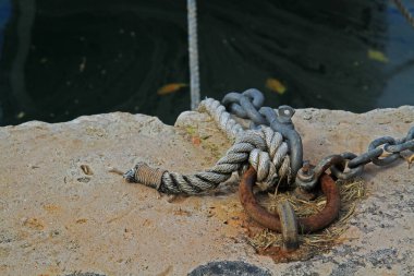 Limandaki bir tekneyi demirlemek için kullanılan halat ve zincirlerin yakın çekimi. 