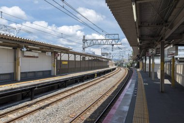 Boş bir Japon tren istasyonu, bir yaz günü demiryolu hattına bakıyor.
