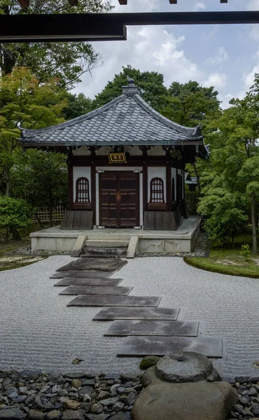 A traditional building in a Japanese Zen Garden. The building has flag stones as a path to get to it