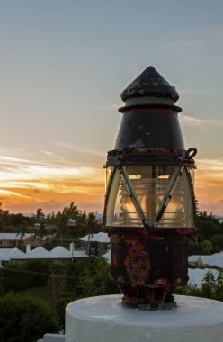 Eski bir deniz feneri, arkasında güneş batıyor.