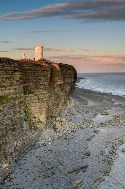 Nash Point Deniz Feneri, Güney Galler, gün batımında. Deniz feneri, Bristol Kanalı 'na bakan sarp kayalıkların tepesinde duruyor.