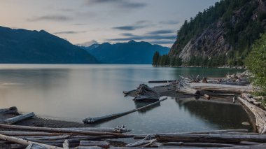 Bir yaz gününün sonunda Porteau Koyu. Su sakindir ve ön planda birçok kütük görülebilir. Mekan BC, Kanada.