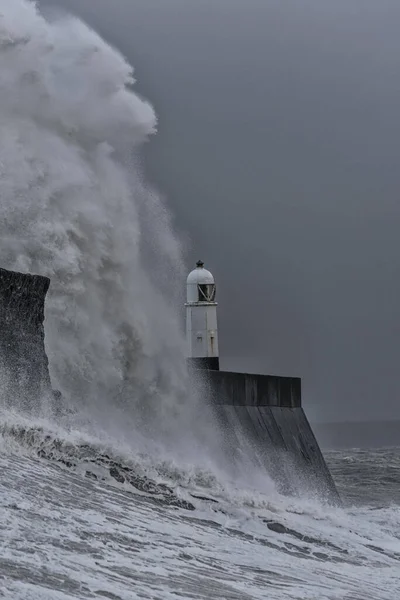 Büyük bir kış fırtınası sırasında, sonunda tek bir deniz feneri olan taştan bir iskeleye karşı dev dalgalar kırılıyor. Mekan Porthcawl, Güney Galler kıyısında..
