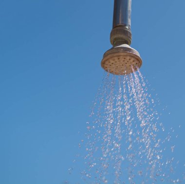 Açık hava duş başlığı, akan suyla, mavi gökyüzüne karşı