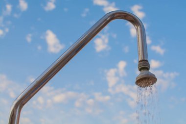 Açık hava duş başlığı, akan suyla, mavi gökyüzüne karşı