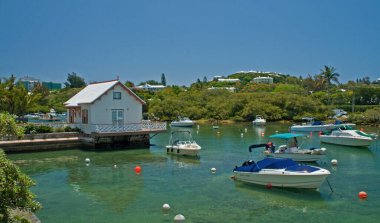 Küçük teknelerin bulunduğu doğal bir limanın üzerine inşa edilmiş bir ev. Mekan Bermuda.