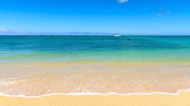 Tropik bir plajın renkli kıyıları. Kum altın sarısıdır, deniz kimliği ise açık deniz mavisi. Kumsal Waikiki plajı, Hawaii.