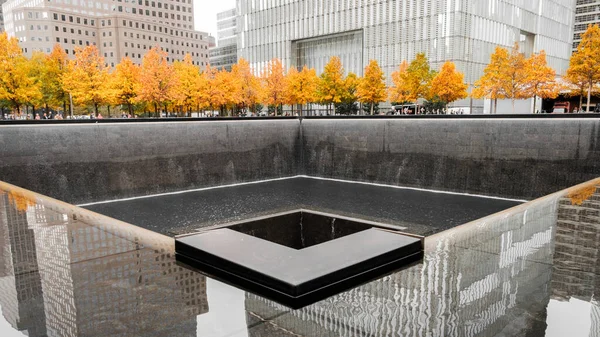 Aşağı Manhattan 'daki 9 / 11 Dünya Ticaret Merkezi Anıtı. Sonbaharda, ağaçlar açık sarı renkte.