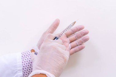 Eldivenli doktor elleri, yaşlanmayı önleyen ve yüz tedavilerini yoğunlaştıran hiyalüronik asit (Ha) tabanlı bir enjeksiyon şişesi tutuyor..