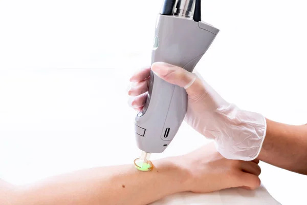 Bir kozmetoloji cilt kliniğinde, tıraş tan sonra epilasyon, güzellik teknisyeni ve kadın hasta ile kol lazer epilasyon oturumu yakın.