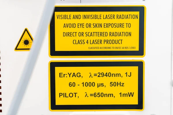 Er: yag laser machine safety label, auf der Geräteseite, in gelb und schwarz, mit Warnungen und Spezifikationen von Laserwellenlängen und -gefahren bei unsachgemäßer Anwendung. Laser der Klasse 4. — Stockfoto