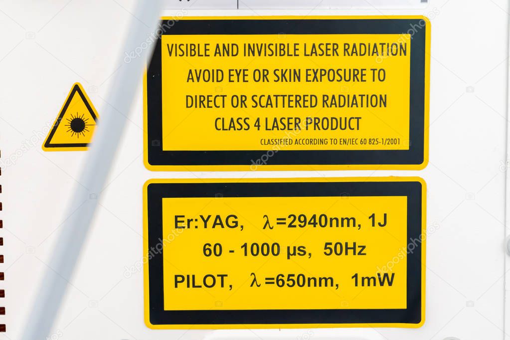 ER:Yag laser machine safety label, on side of device, in yellow and black, with warnings and specifications of laser wavelengths and dangers if not used properly. Class 4 laser product.