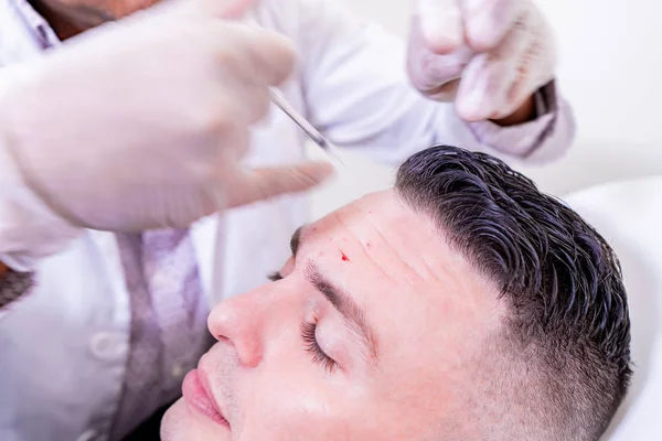 Caucasian man undergoing beauty spa botulinum neurotoxin Botox treatment for anti-aging, to smooth wrinkles as a cometic solution. Injecting forehead to relax muscles with a non-invasive procedure. — Stock Photo, Image