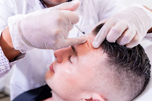 Homme caucasien subissant beauté spa botulinum neurotoxine Botox traitement anti-âge, pour lisser les rides comme une solution cométique. Injection du front pour détendre les muscles avec une procédure non invasive . — Photo