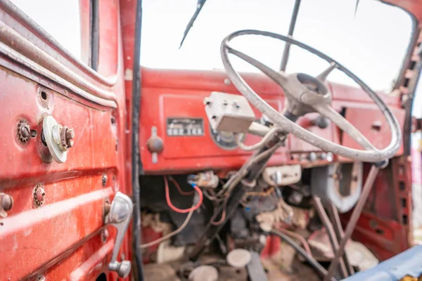 Régi, kopott, rusztikus, vörös traktor belseje törött alkatrészekkel és kitett vezetőfelülettel — Stock Fotó