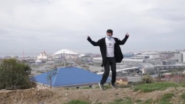 Genç maskeli adam Coronavirus Covid-19 'un arka planında dans ediyor.