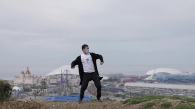 Genç maskeli adam Coronavirus Covid-19 'un arka planında dans ediyor.