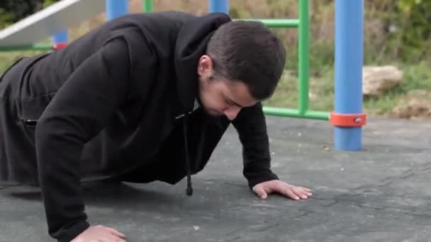 Un jeune homme dans l'aire de jeux fait du sport. se tordre — Video