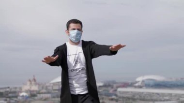 Genç maskeli adam Coronavirus Covid-19 'un arka planında dans ediyor.