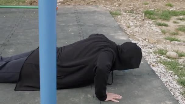 Un joven enmascarado en el patio de recreo hace deporte. estrujar — Vídeos de Stock