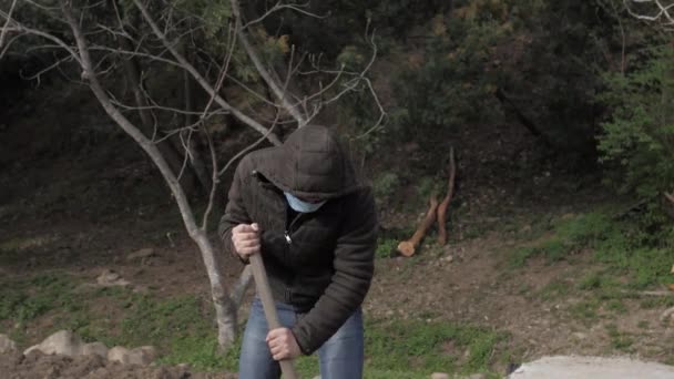 Kaukasisk kille i mask gräver i trädgården karantän själv isolering — Stockvideo