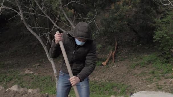 マスク中の白人男性が庭の隔離性的隔離を掘り — ストック動画